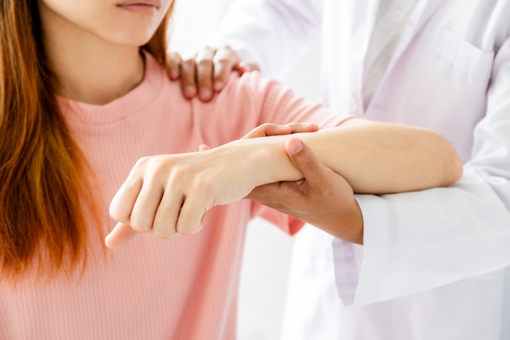 Female doctor hand rehab physical therapy by extending the pain shoulder of a patient. treatment with stretch exercises.