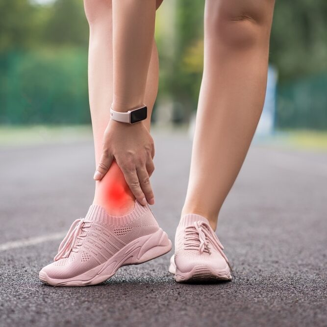 Achilles tendon injury, callus on the heel while running, foot pain, woman suffering from feet ache on a sports ground, podiatry concept.